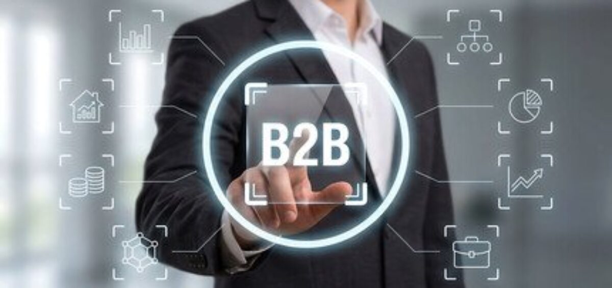 Business professional holding a B2B interface surrounded by digital sales and analytics icons.