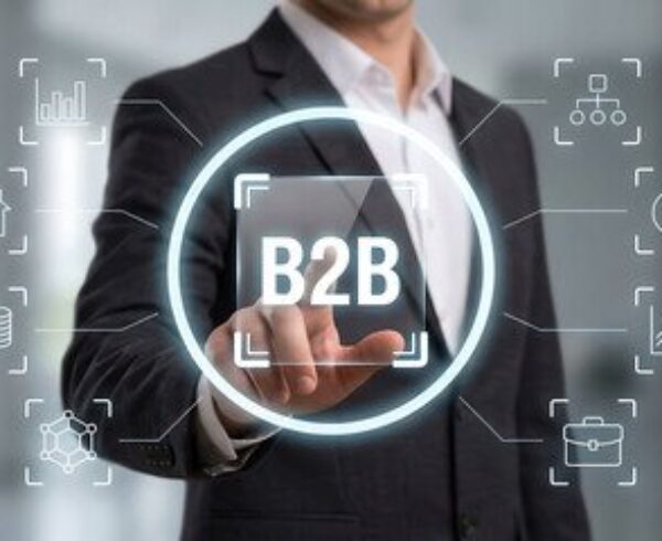 Business professional holding a B2B interface surrounded by digital sales and analytics icons.
